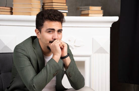 A man smiling politely at work while looking tired and sad in his eyes, reflecting the hidden struggle of high-functioning depression.