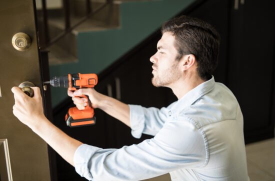 A man standing at his front door, holding the doorknob with worry as he checks the lock multiple times before leaving.
