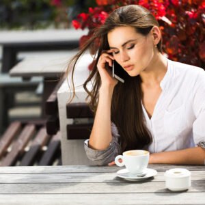 A woman sitting at a café table, looking uncomfortable as she agrees to something she does not want to do.