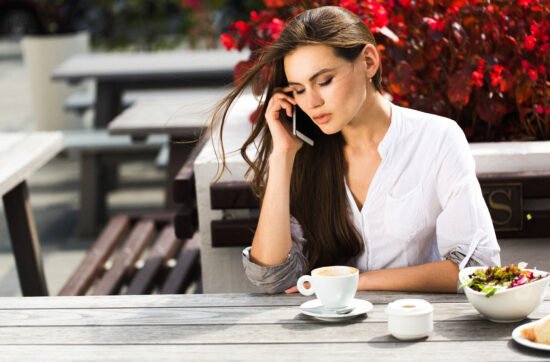 A woman sitting at a café table, looking uncomfortable as she agrees to something she does not want to do.